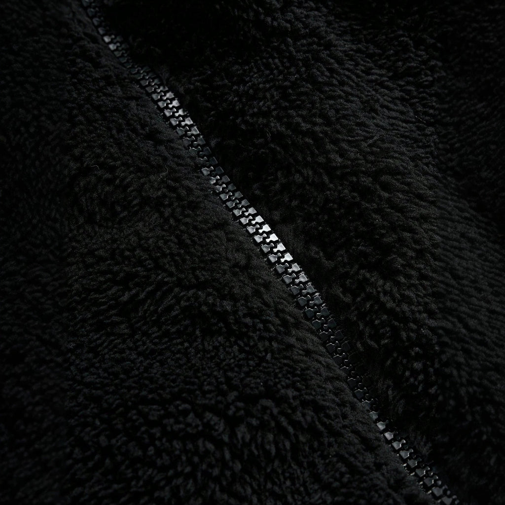 Veste de fourrure noire avec une fermeture éclair et broderie sur la poitrine gauche