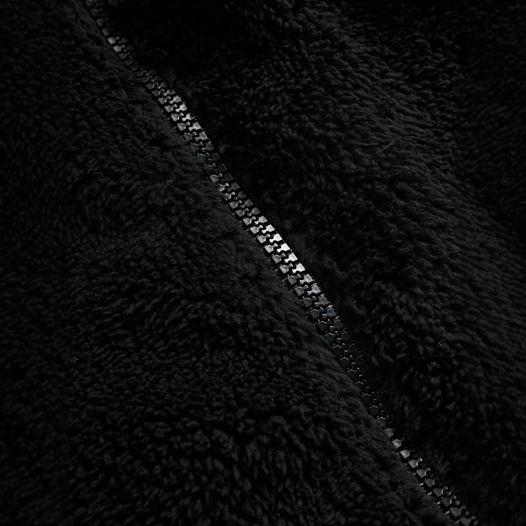 Veste de fourrure noire avec une fermeture éclair et broderie sur la poitrine gauche