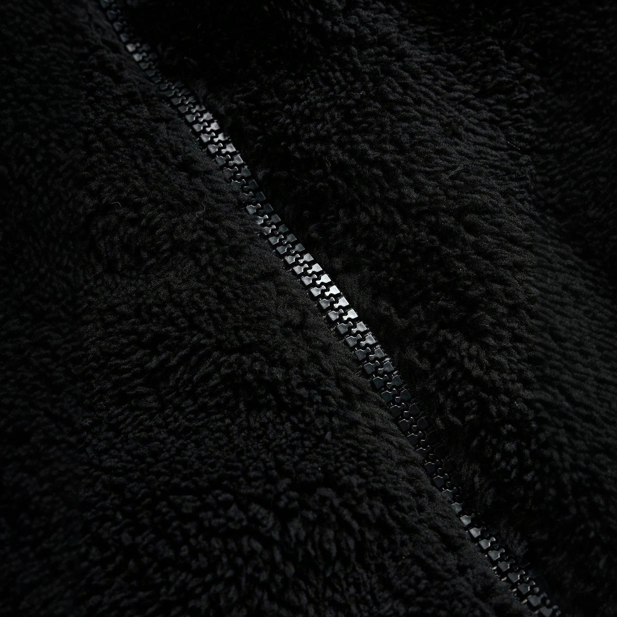 Veste de fourrure noire avec une fermeture éclair et broderie sur la poitrine gauche