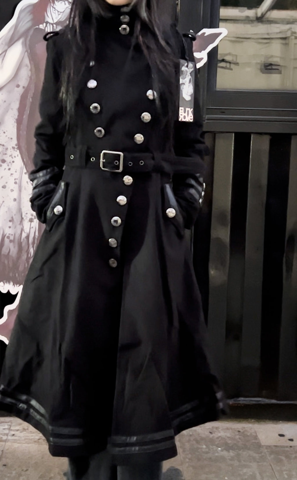 Short punk-style coat, longer at the back than at the front, with a fitted waist