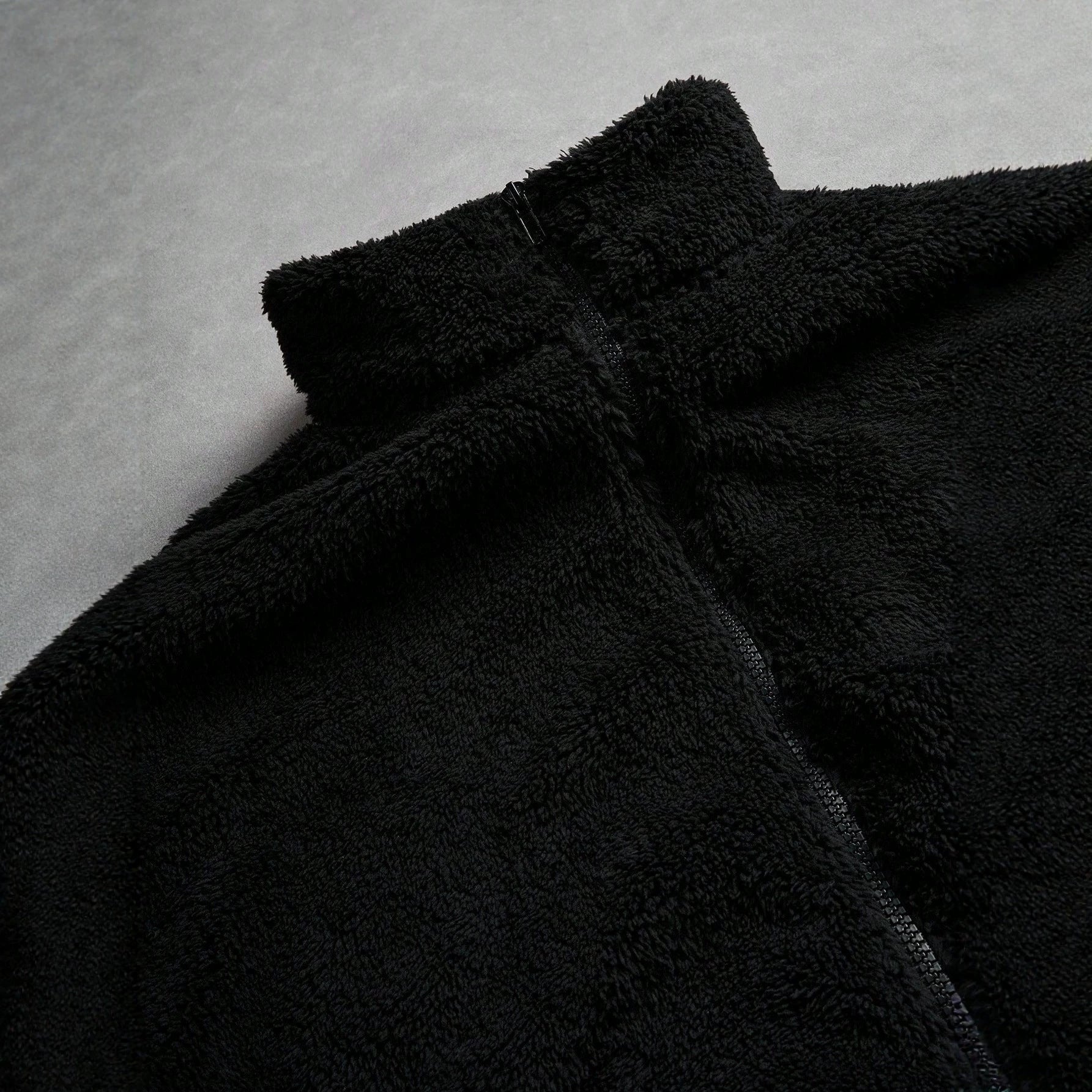 Veste de fourrure noire avec une fermeture éclair et broderie sur la poitrine gauche
