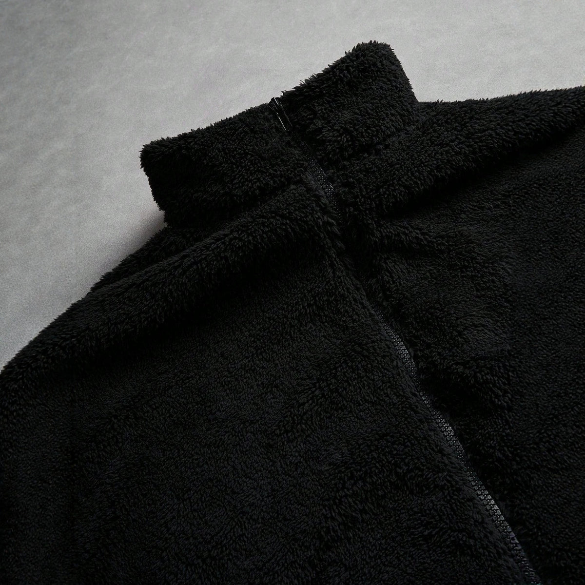 Veste de fourrure noire avec une fermeture éclair et broderie sur la poitrine gauche